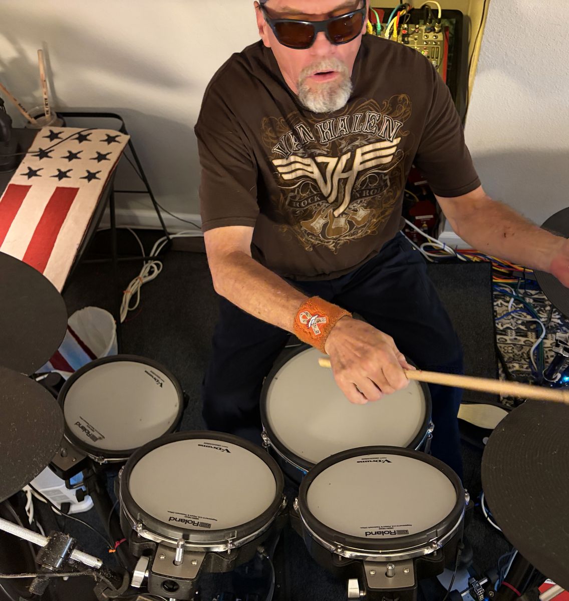 Russ, in sunglasses and a Van Halen T-shirt, playing the Roland
                  TD-27 V-Drums kit, seen from above the pads.