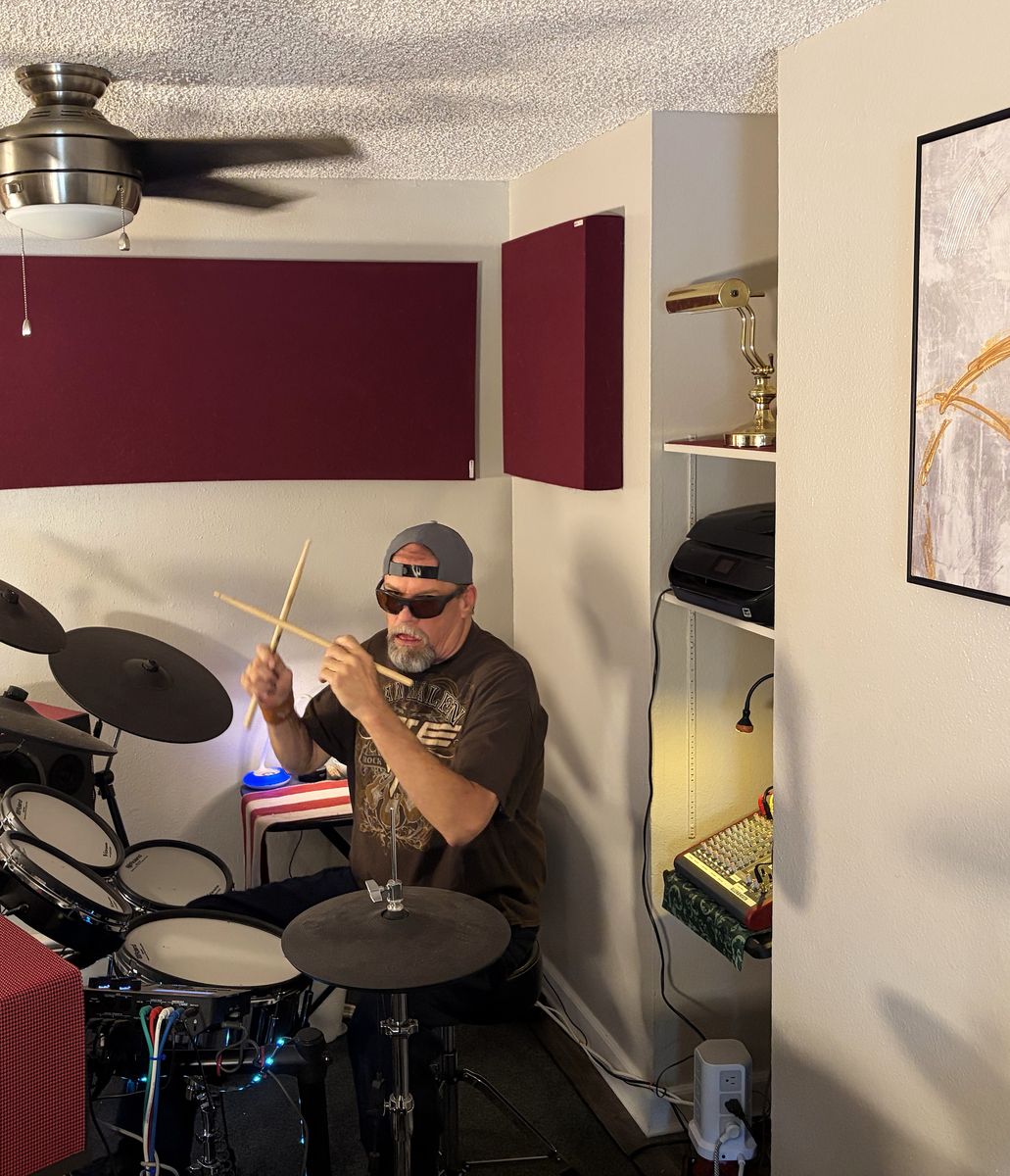 The drum room: Russ at the V-Drums kit, with acoustic
                  panels on the wall behind.
